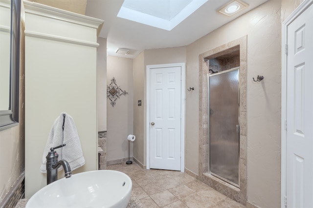 bathroom with a skylight, tile patterned flooring, and a shower with door