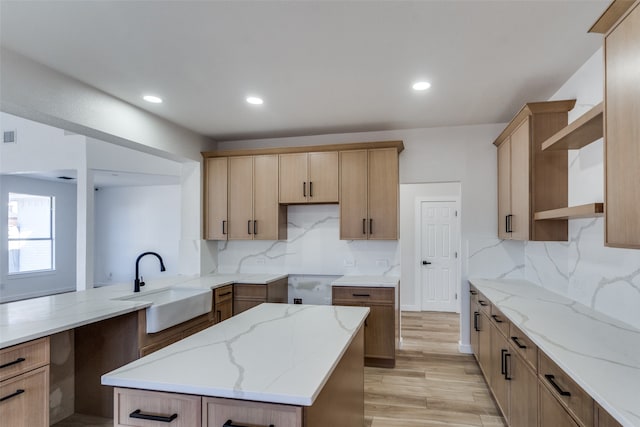 kitchen with light hardwood / wood-style floors, light stone counters, sink, and tasteful backsplash