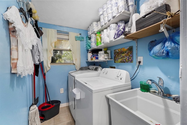 laundry area featuring sink, independent washer and dryer, light tile patterned floors, and a textured ceiling