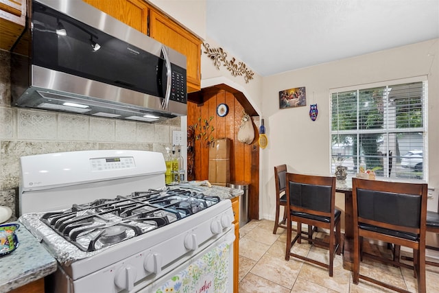 kitchen with backsplash, light tile patterned floors, and white range with gas cooktop