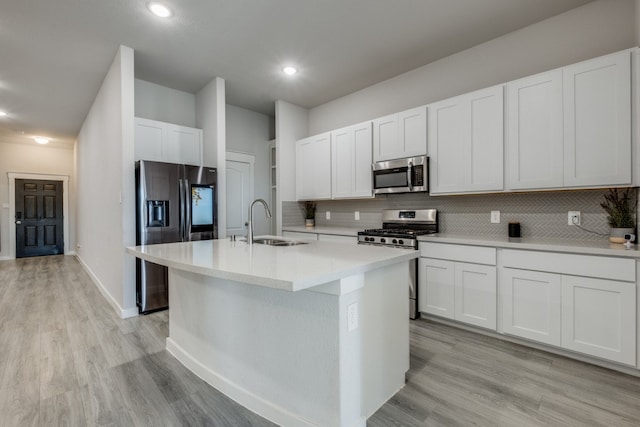 kitchen with white cabinetry, stainless steel appliances, a center island with sink, and sink