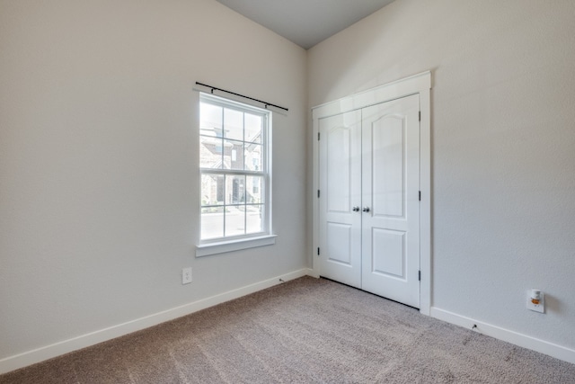 unfurnished bedroom with light colored carpet and a closet