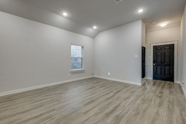 unfurnished room with light wood-type flooring and vaulted ceiling