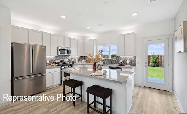 kitchen with a kitchen breakfast bar, white cabinetry, a center island, and stainless steel appliances