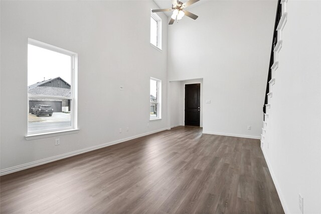 dining space with ceiling fan, light wood-type flooring, and a towering ceiling