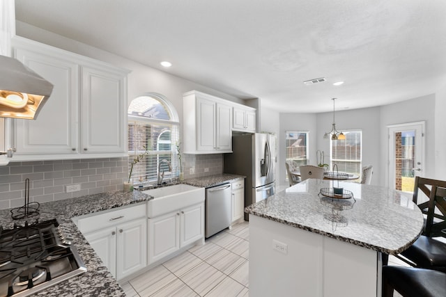 kitchen featuring white cabinetry, sink, decorative backsplash, a kitchen island, and appliances with stainless steel finishes