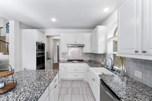 kitchen featuring white cabinets, appliances with stainless steel finishes, dark stone counters, and sink