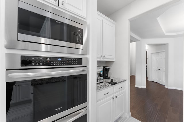 kitchen featuring white cabinetry, dark hardwood / wood-style flooring, light stone countertops, and appliances with stainless steel finishes