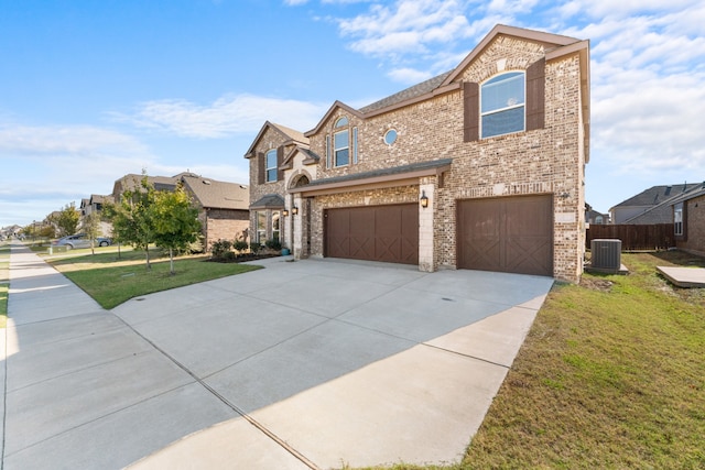 view of front of property featuring cooling unit, a garage, and a front lawn