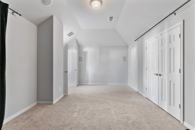 interior space featuring a textured ceiling, light colored carpet, and vaulted ceiling