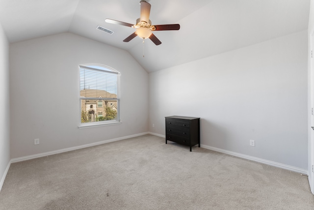 empty room featuring ceiling fan, lofted ceiling, and light carpet