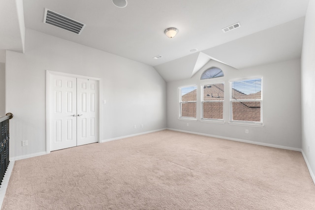 unfurnished bedroom with light carpet, vaulted ceiling, and a closet