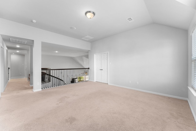 carpeted empty room with vaulted ceiling