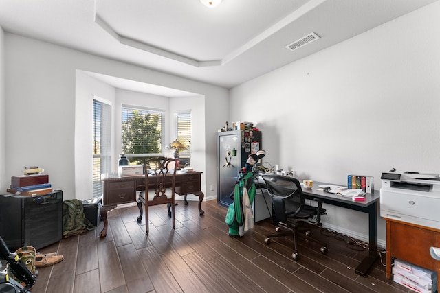 home office with a tray ceiling and dark hardwood / wood-style floors