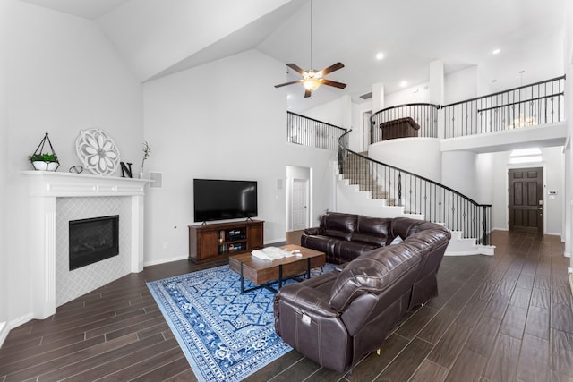 living room with a tile fireplace, high vaulted ceiling, ceiling fan, and dark wood-type flooring