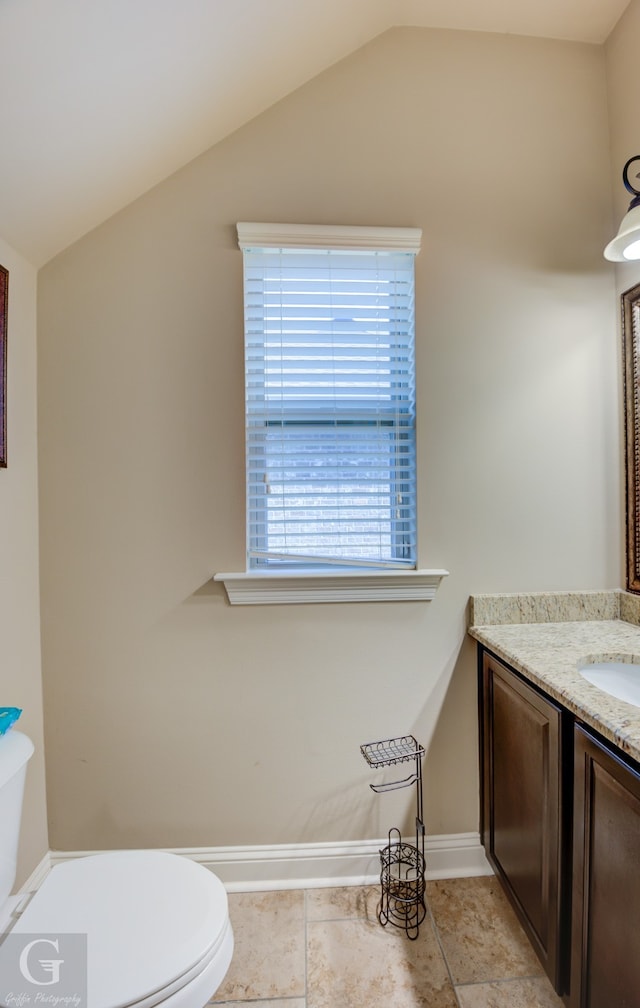 bathroom with lofted ceiling, tile patterned floors, toilet, and vanity