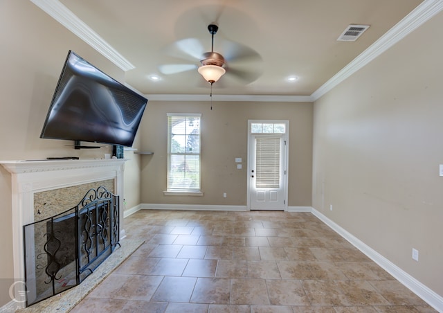 unfurnished living room with a premium fireplace, ceiling fan, and ornamental molding