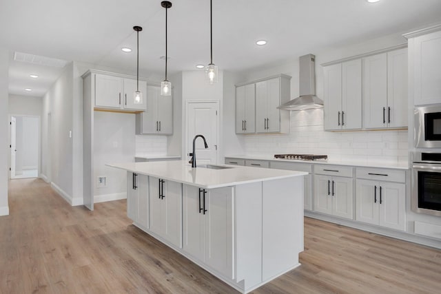 219 Briarwood Dr, Nevada, TX 75173 - kitchen featuring wall chimney range hood, appliances with stainless steel finishes, decorative backsplash, light wood-style floors, and recessed lighting
