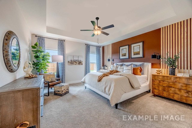 carpeted bedroom with a tray ceiling and ceiling fan