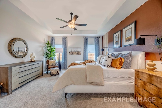 carpeted bedroom featuring ceiling fan and a tray ceiling