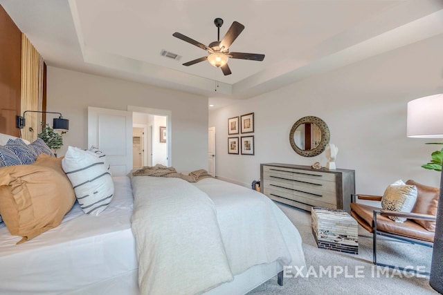 carpeted bedroom featuring a tray ceiling and ceiling fan