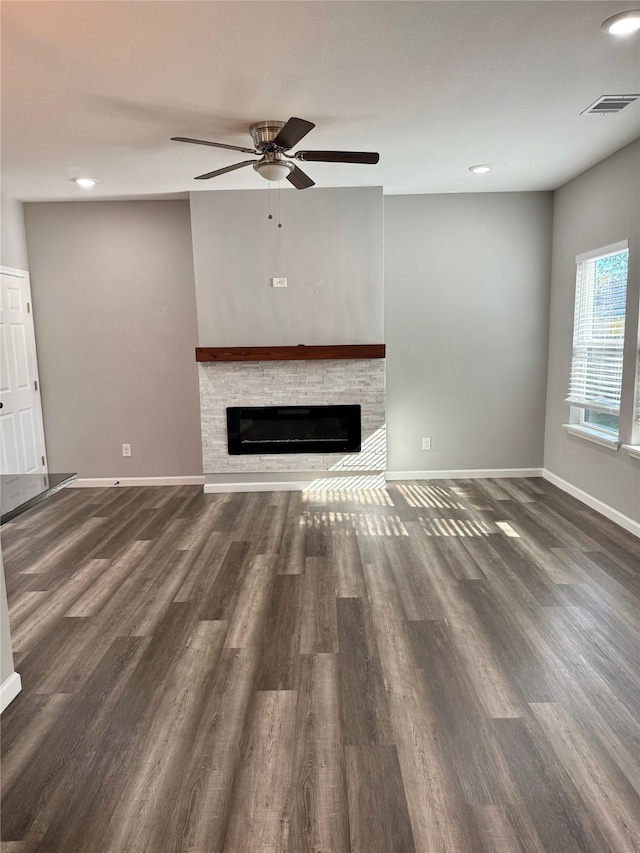 unfurnished living room featuring a fireplace, ceiling fan, and dark wood-type flooring