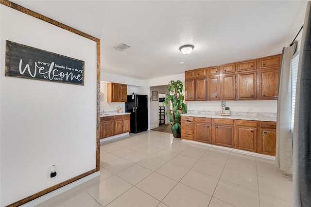 kitchen with light tile patterned flooring and black refrigerator