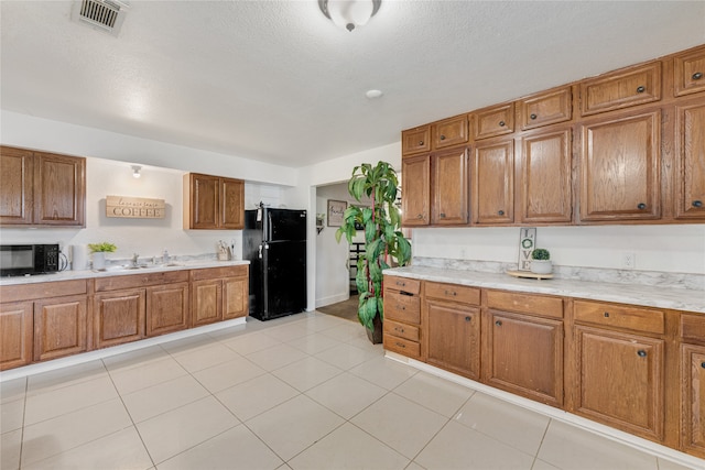 kitchen with black appliances, sink, light tile patterned floors, and a textured ceiling