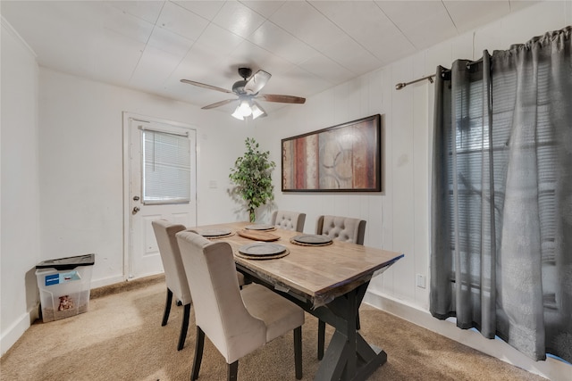 carpeted dining space with wooden walls and ceiling fan