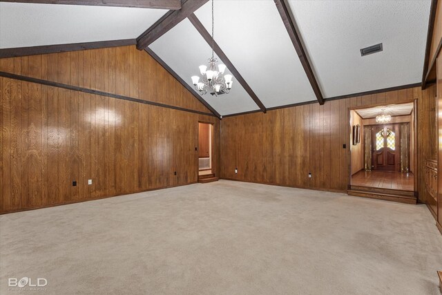 unfurnished living room with wood walls, light colored carpet, and a notable chandelier