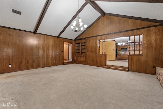 unfurnished living room with lofted ceiling with beams, light colored carpet, wood walls, and an inviting chandelier