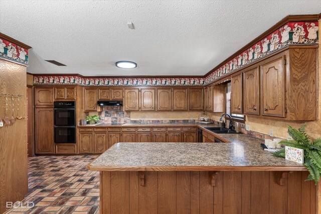 kitchen with a textured ceiling, kitchen peninsula, black appliances, and sink