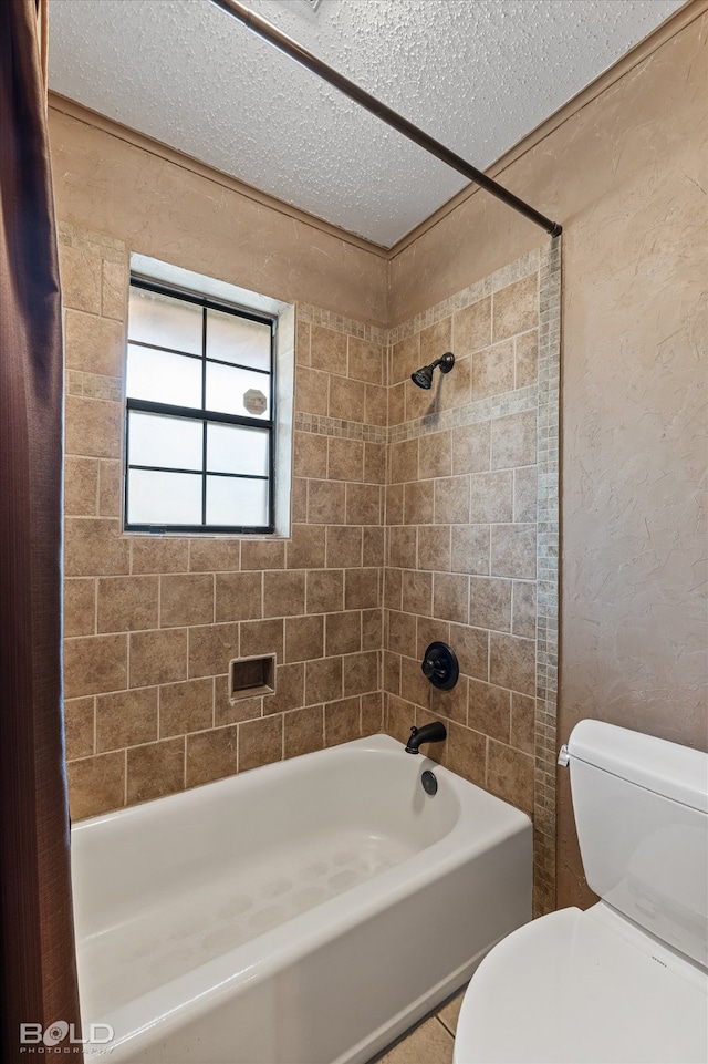 bathroom with toilet, tiled shower / bath, and a textured ceiling