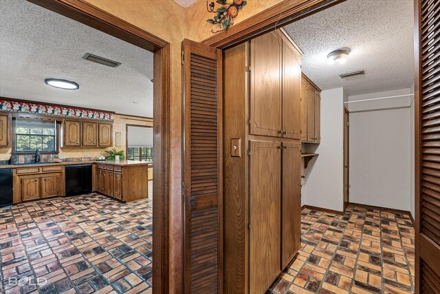 kitchen featuring dishwasher, sink, and a textured ceiling