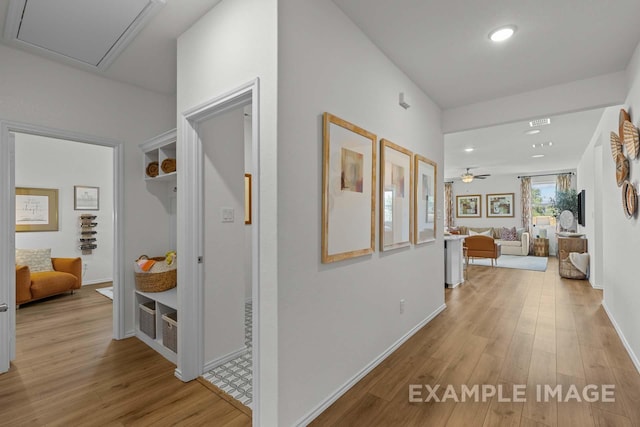 hallway with light wood finished floors, recessed lighting, attic access, and baseboards