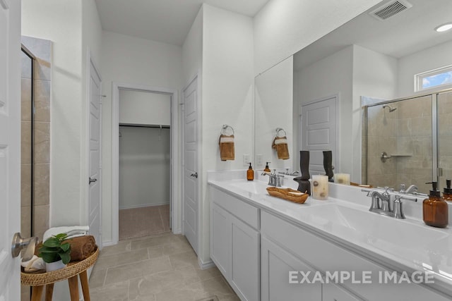 bathroom with a shower stall, a spacious closet, visible vents, and a sink