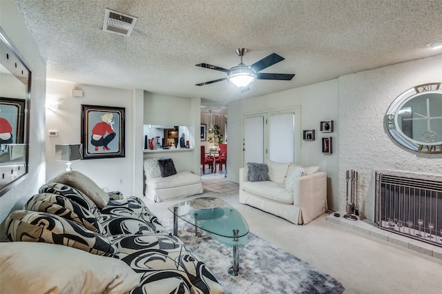 carpeted living room featuring ceiling fan, a textured ceiling, and a large fireplace