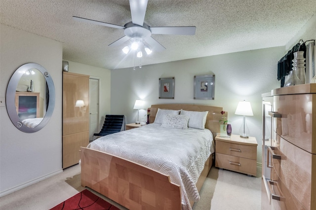 bedroom featuring ceiling fan, light colored carpet, a closet, and a textured ceiling