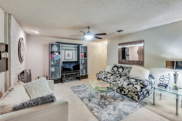 carpeted living room featuring ceiling fan and a textured ceiling