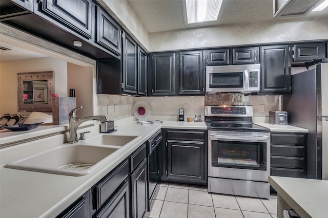 kitchen featuring backsplash, appliances with stainless steel finishes, sink, and light tile patterned floors