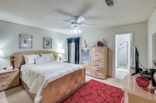 bedroom with ensuite bathroom, light carpet, ceiling fan, and a textured ceiling