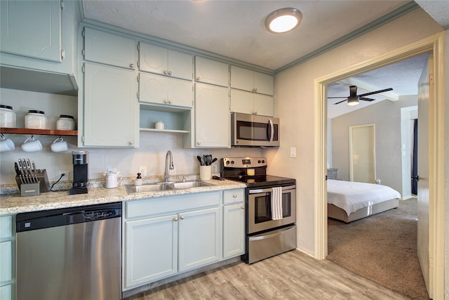 kitchen featuring stainless steel appliances, light hardwood / wood-style floors, sink, ceiling fan, and white cabinets