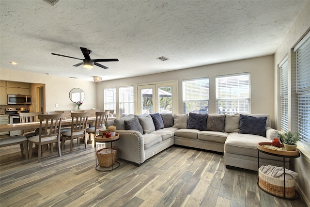 living room featuring hardwood / wood-style floors, ceiling fan, and a textured ceiling