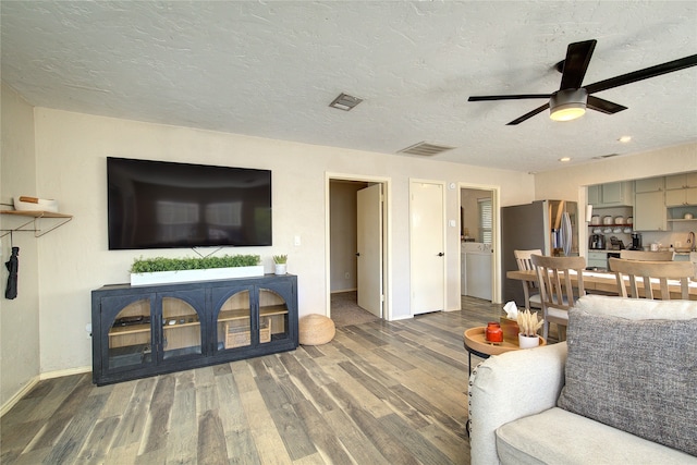 living room with wood-type flooring, ceiling fan, and a textured ceiling