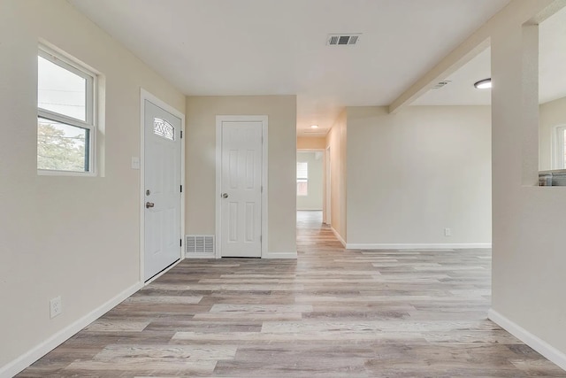 entrance foyer with beamed ceiling, plenty of natural light, and light hardwood / wood-style flooring