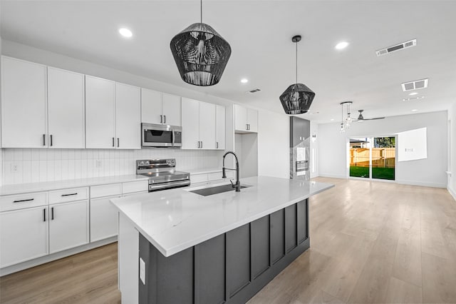 kitchen featuring white cabinets, a center island with sink, sink, and appliances with stainless steel finishes