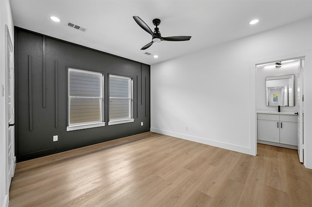 unfurnished bedroom featuring ceiling fan, ensuite bath, and light wood-type flooring