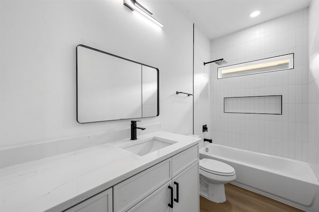 full bathroom featuring hardwood / wood-style floors, vanity, toilet, and tiled shower / bath combo