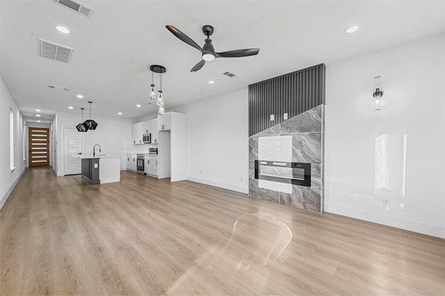 unfurnished living room featuring ceiling fan, sink, and light hardwood / wood-style floors