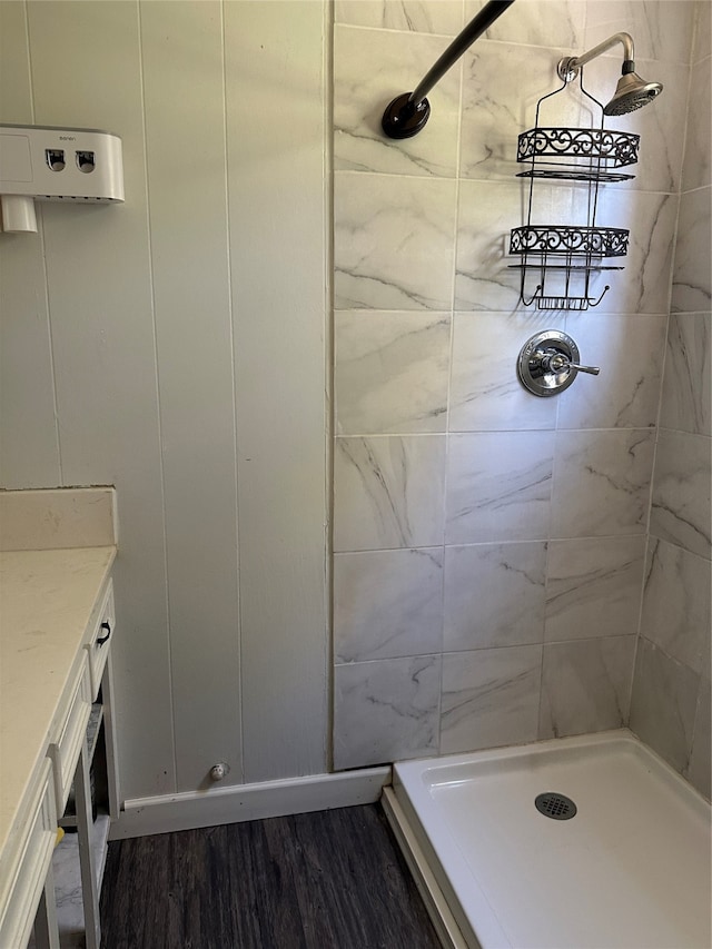 bathroom with hardwood / wood-style flooring, vanity, and a tile shower